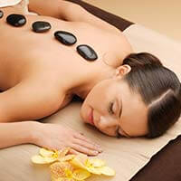 A woman laying on the ground with hot stones in her back.